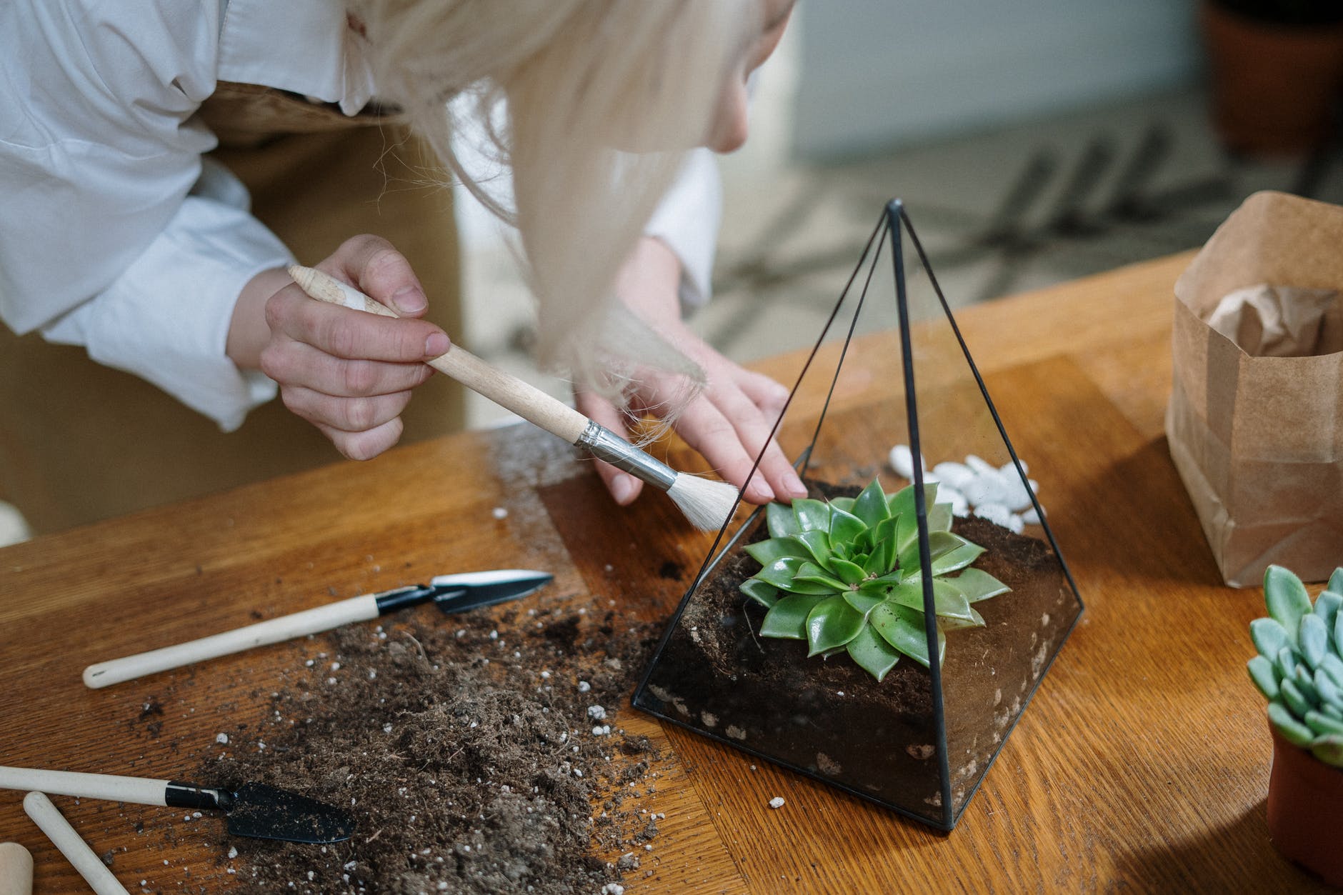 person holding white chopsticks and green vegetable on brown wooden chopping board